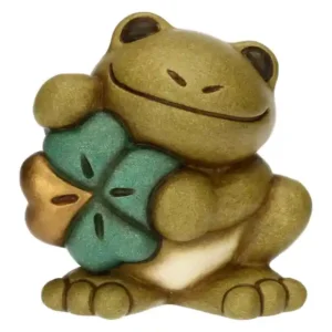 Mini rana Thun in ceramica color verde oliva con occhi neri e bocca sorridente, che tiene in grembo un quadrifoglio verde e oro.