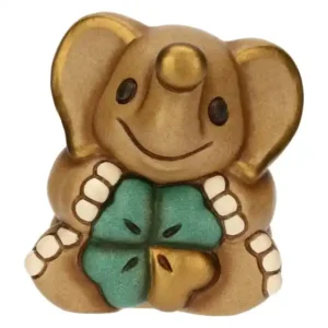 Mini elefante Thun in ceramica color marrone chiaro con occhi neri e proboscide dorata, che tiene in grembo un quadrifoglio verde e oro.