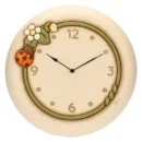 Orologio da parete THUN maxi in ceramica color crema con cornice interna verde, numeri in rilievo, coccinella rossa e fiori bianchi decorativi.