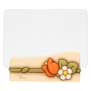 Portafoto THUN con base in ceramica color crema decorata con un fiore arancione e un fiore bianco con bocciolo e un nastro verde, e una lastra di vetro trasparente.
