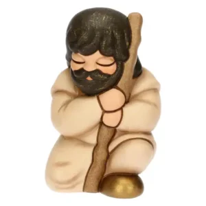 Statuina in ceramica Thun raffigurante un pellegrino del presepe classico con bastone, tunica beige e dettagli dorati.